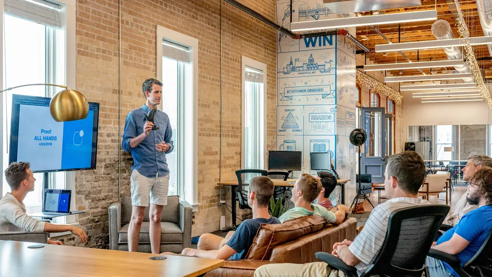 Team lead speaking during a company all-hands meeting in a modern office