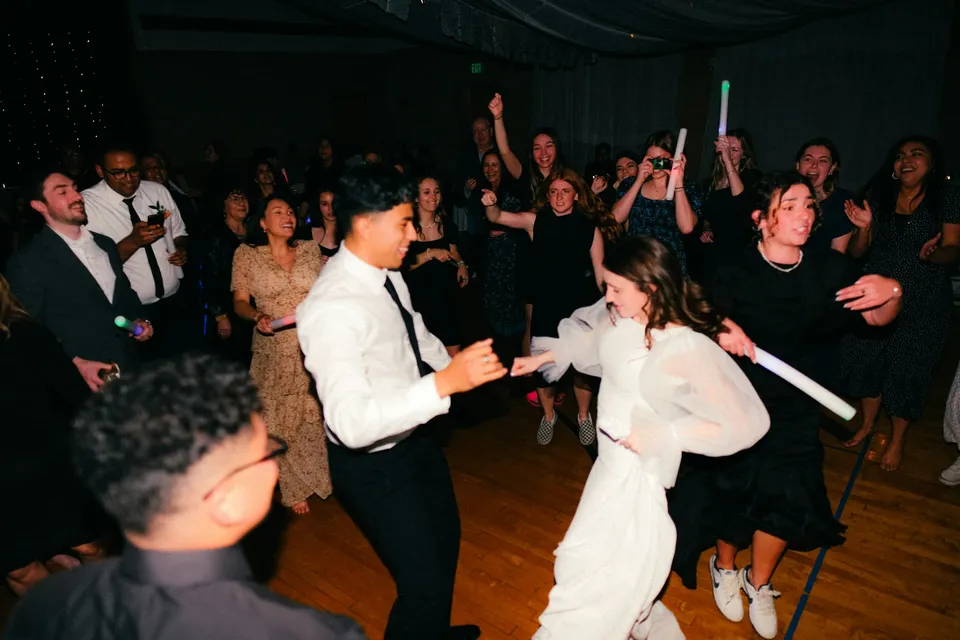 Bride and groom dancing at their reception with guests holding glow sticks