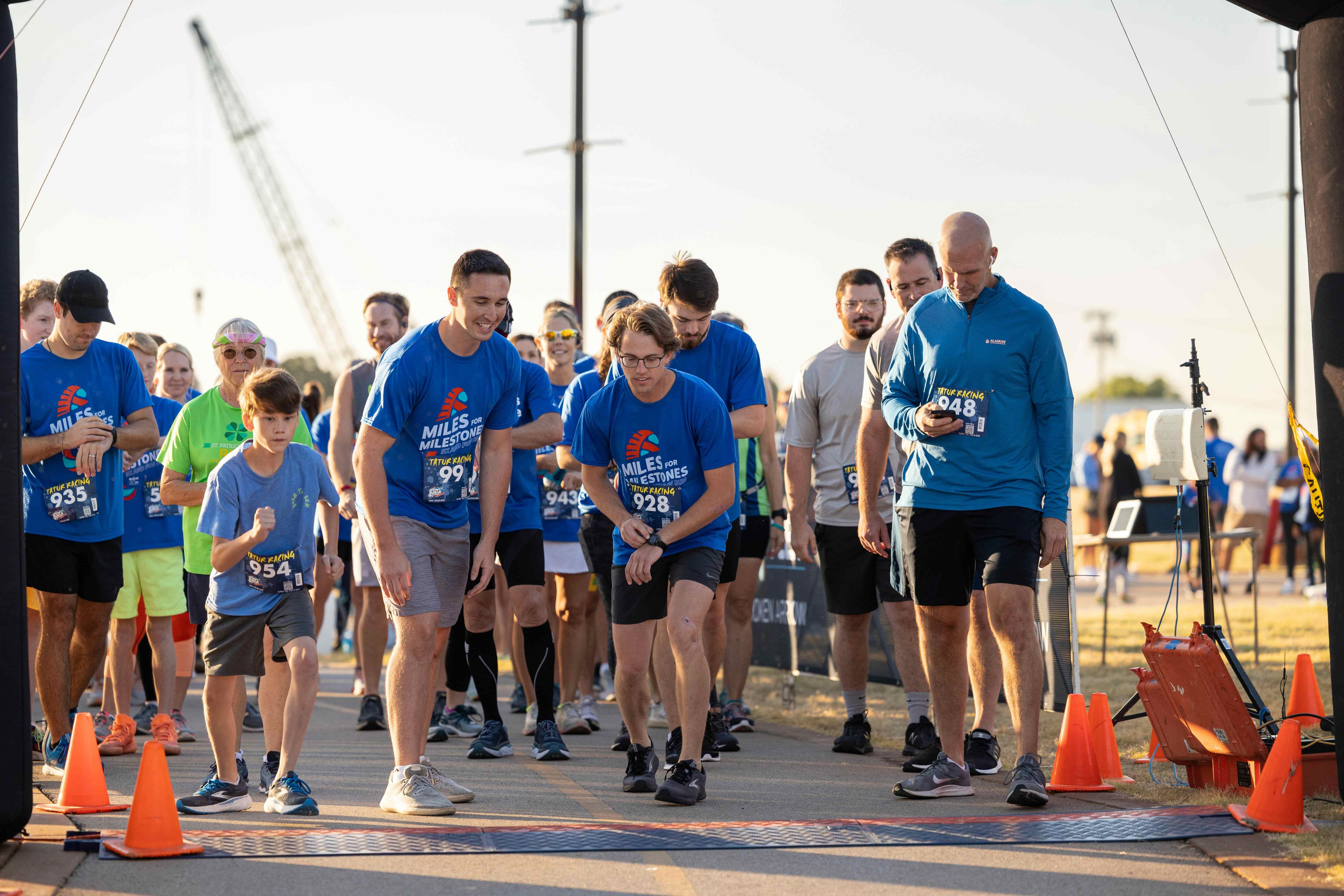 Race participants crossing the finish line while volunteers capture photos on their phones